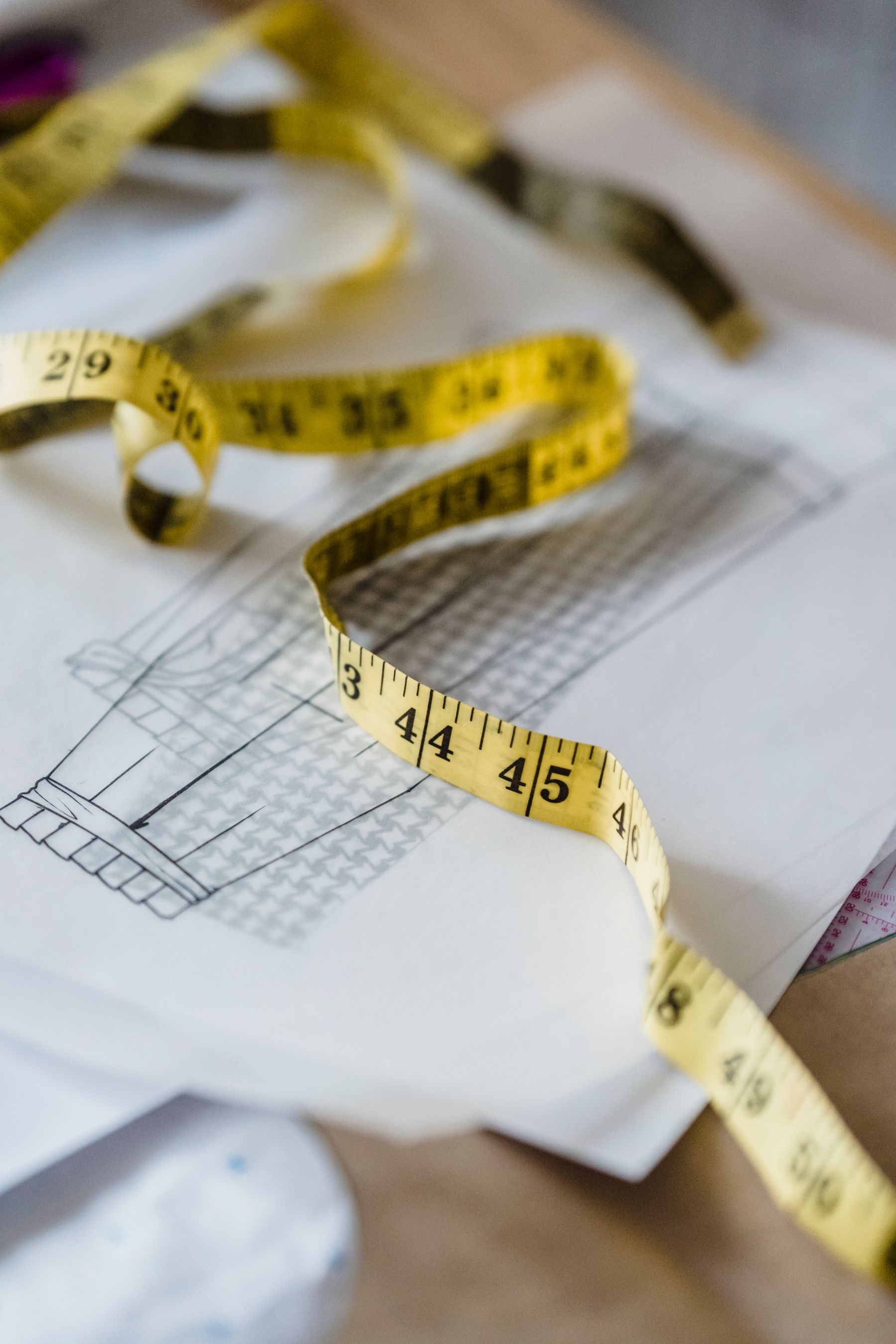 Tape measure laid over architectural sketches